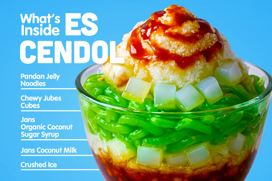 Glass of Es Cendol with pandan jelly noodles, nata de coco cubes, shaved ice, coconut milk, and palm sugar syrup.
