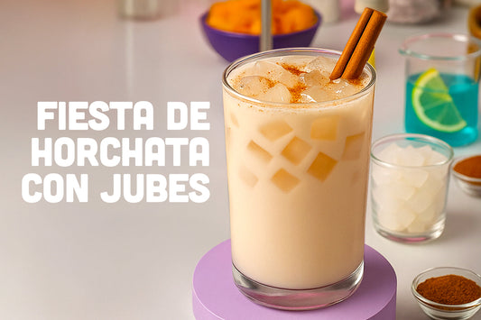 Glass of horchata with ice cubes and chewy coconut jelly, topped with cinnamon sticks, surrounded by small bowls of ingredients, with text that reads 'Fiesta de Horchata con Jubes'.