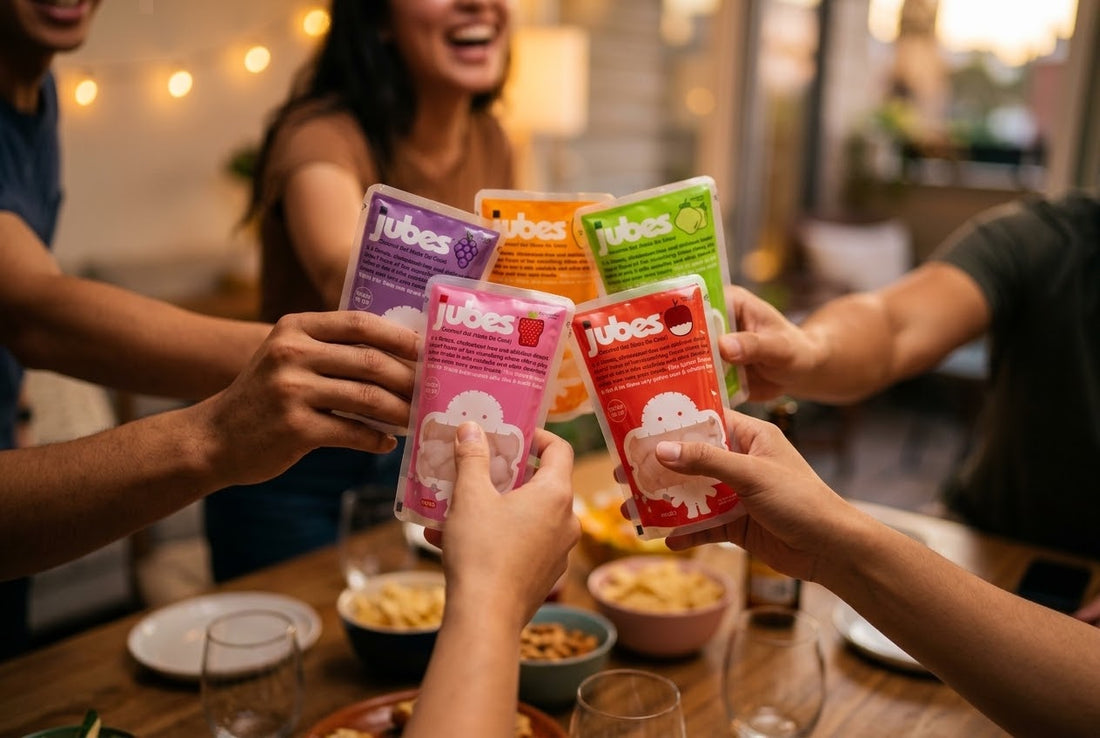 Five friends clink colorful Jubes coconut jelly pouches together over a table with snack bowls and string lights in the background.