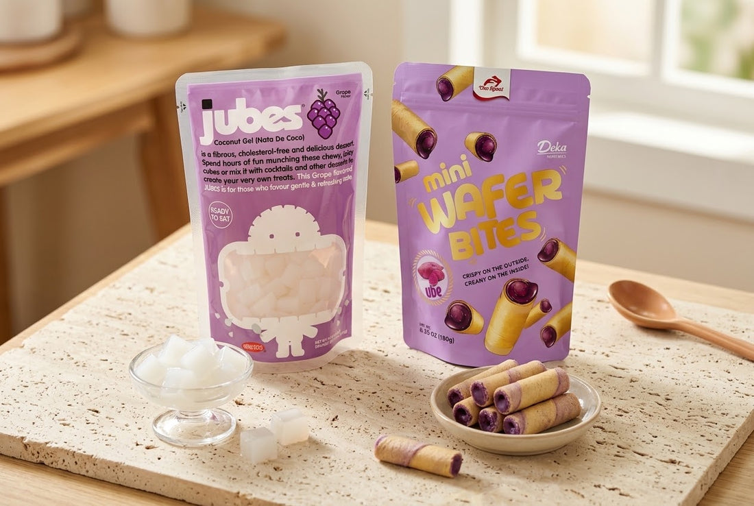 A Jubes Grape coconut jelly pouch next to a Deka Ube Mini Wafer Bites pouch, with loose coconut cubes and wafer rolls in small dishes.