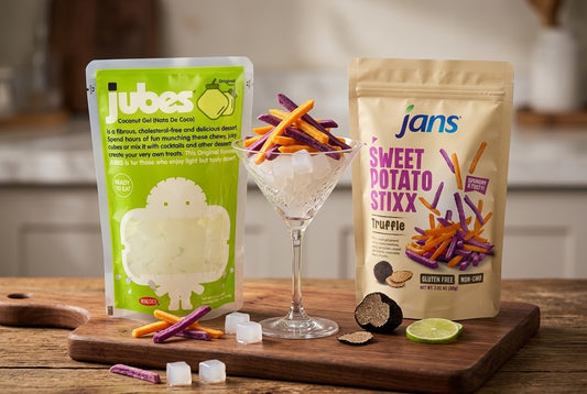 A Jubes Original pouch and Jans Sweet Potato Stixx Truffle pouch beside a glass of stixx and ice, with truffle shavings and lime.
