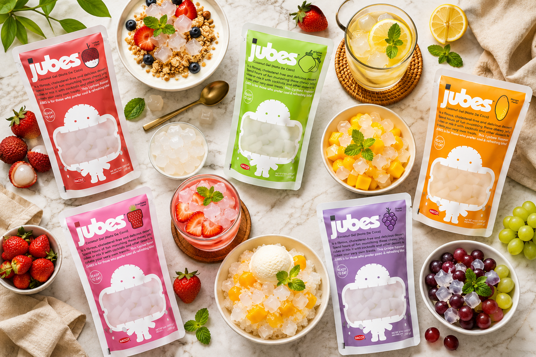 Jubes nata de coco pouches arranged with desserts and drinks, showing coconut jelly cubes served in yogurt bowls, shaved ice, fruit bowls, and refreshing beverages on a bright marble table.