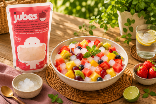 Colorful tropical fruit salad with nata de coco jelly cubes and Jubes Lychee Coconut Gel pouch on a sunlit wooden table.