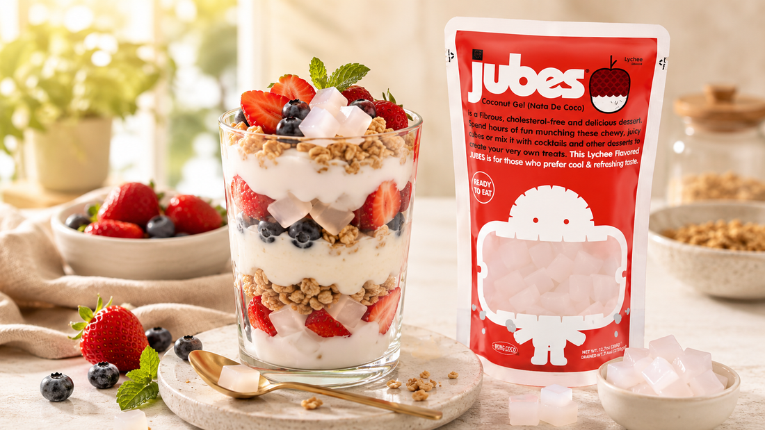 A layered fruit and yogurt parfait with jelly cubes next to a red pouch of Jubes Coconut Gel