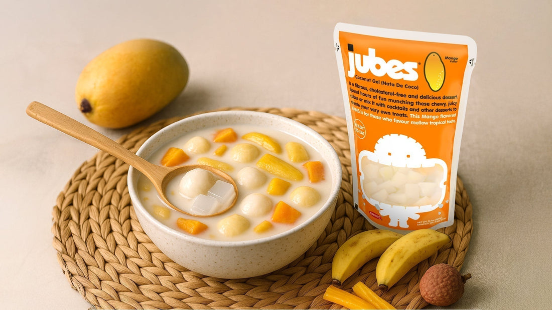 Bowl of Filipino ginataang bilo-bilo dessert with coconut milk, chewy rice balls, sweet potato, and jackfruit, placed next to an orange Jubes nata de coco pack and fresh tropical fruits.