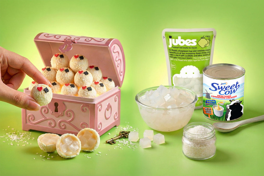 Coconut dessert balls filled with Jubes nata de coco displayed in a pink treasure box, with ingredients including a bowl of coconut gel, shredded coconut, and Sweet Cow condensed creamer on a green background.