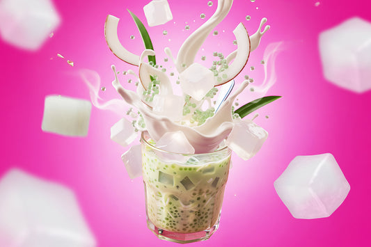 Iced pandan coconut drink with nata de coco cubes splashing in creamy milk against a bright pink background.