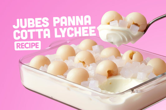 Jubes panna cotta lychee dessert topped with chewy nata de coco cubes and lychee fruit on a pink background.