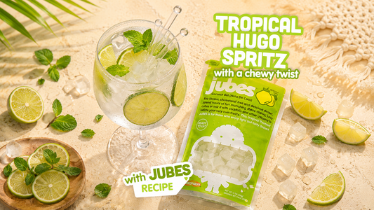 Iced Hugo Spritz mocktail with lime and mint beside a bag of Jubes Original Nata De Coco coconut jelly for a refreshing summer drink.
