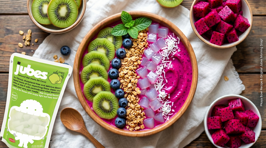 Bright pink pitaya smoothie bowl topped with kiwi slices, blueberries, coconut flakes, almond butter, and chewy Jubes Nata De Coco coconut jelly cubes in a tropical breakfast setting.