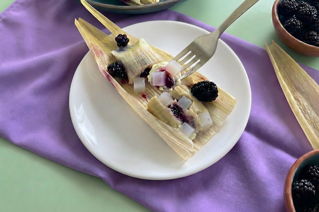 Steamed tamale-style dessert topped with blackberries and nata de coco, served on a white plate.